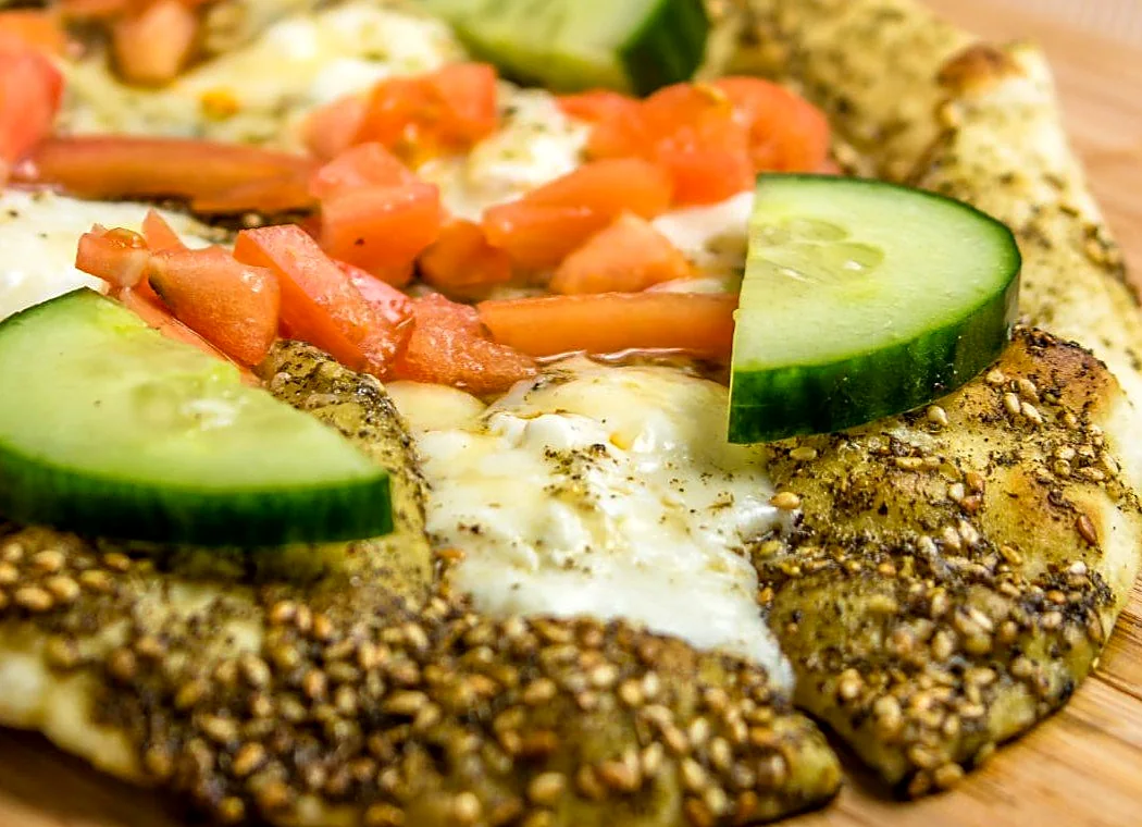 Half za'atar, half cheese man'oushe with cucumber and tomato